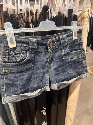 Lågmidjade jeansshorts  - Säljer ett par blå lågmidjade jeansshorts med snygga fickdetaljer. Shortsen har uppvikta benslut och klassisk femficksdesign. Står ingen stolek men skulle säga att de är en S-M. Säljer då de tyvärr är för små.