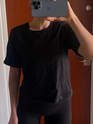 Svart basic t-shirt  - En enkel svart t-shirt med rund hals och korta ärmar. Modellen är rak och något loose fit,  perfekt till jeans eller tights. Tillverkad i mjuk bomull för skön känsla hela dagen. Bra skick men skrynklig (behövs strykas till).