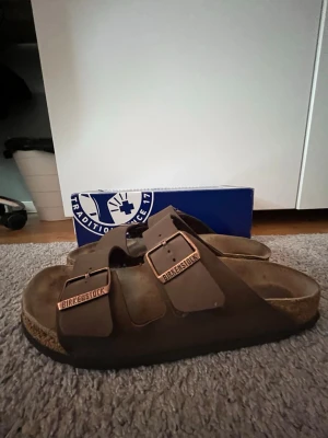 🔥Birkenstock Arizona 🔥 - Säljer dessa as feta Birkenstock Arizona🔥.      Storlek 41 (passar även 40-42)  Tofflorna är väl omhändertagana och är i mycket bra skick 💎.  Orginal pris är 1100 kr med jag säljer dessa för 399 kr 💸💎 Tofflorna är perfekt till sommaren !!!        Hör av dig vid frågor och funderingarna 📲