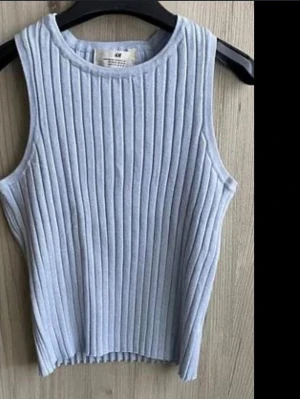 Ljusblå ribbad ärmlös topp H&M - Säljer en ljusblå ribbad ärmlös topp från H&M. Toppen har en rund halsringning och är tillverkad i ett mjukt, stretchigt material som sitter snyggt på kroppen. Perfekt att styla med jeans eller kjol för en clean look.