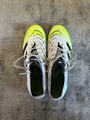 Adidas Predator fotbollsskor vit/gul, konstgräs - Säljer mina Adidas Predator Elit i storlek 42 2/3. Underlaget är konstgräs. Skorna har används ett tiotal gånger och är i väldigt bra skick. Påse ingår.