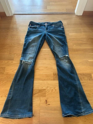 Blå bootcut jeans från True Religion - Säljer ett par blå bootcut jeans från True Religion med slitningar vid knäna. I Strl. W26💗