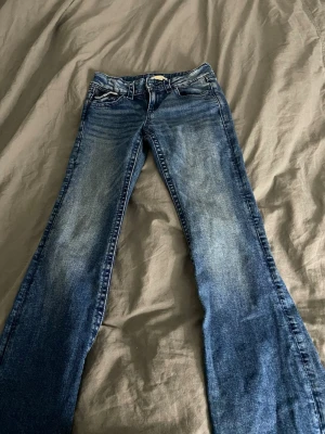  bootcut jeans med rosett-detalj - Blåa bootcut jeans som inte använts mer en 1-2 gånger för att dom har varit för långa med rosetter på fickorna