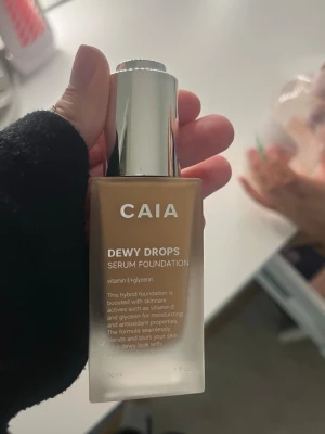 CAIA Dewy Drops Serum Foundation 30W - Foundation från CAIA i nyansen 30W. Dewy Drops Serum Foundation ger en fräsch, daggig finish och innehåller vitamin E och glycerin för återfuktning. Kommer i en stilren glasflaska med silverfärgad pump. Perfekt för dig som vill ha en naturlig glow. Endast använd en gång, säljer för det var fel shade