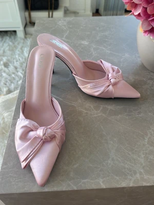 Klackar  - Rosa klackar med rosett. Aldrig använda. Jag brukar ha 38 men dessa passar mig💕Har ingen linjal men med ögonmått skulle jag gissa att de är ca 8 cm höga 