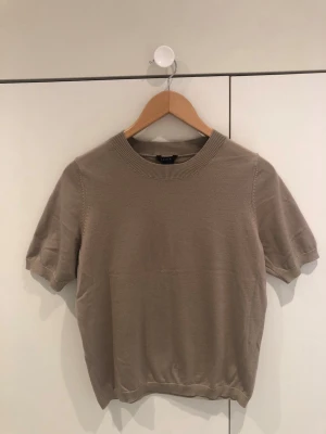 Beige kortärmad tröja från Lindex - Snygg beige stickad tröja från Lindex i storlek S. Tröjan har korta ärmar, rund halsringning och ribbade kanter. Perfekt för en stilren och enkel look. Materialet känns mjukt och lätt mot huden. Använd endast ett fåtal gånger. Är öppen med prisförslag😊