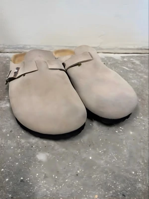 Beige Birkenstock Boston tofflor - Säljer ett par helt nya beige Birkenstock Boston tofflor i mocka med justerbart spänne.