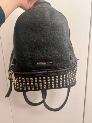 Michael Kors ryggsäck säljes. - Snygg och praktisk ryggsäck i bra skick. En av dragkedjorna är trasig, vilket syns på bilderna. Därför säljer jag väskan till ett lägre pris.  I övrigt är väskan fin och passar perfekt för den som vill laga dragkedjan och göra ett bra fynd.  Kontakta mig gärna om du har frågor eller vill se fler bilder.