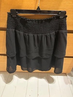 ONLY Svart Volangkjol - Jättefin svart kjol från ONLY i storlek S. Säljer då den är lite stor på mig och därför aldrig använts, och har därför ingen egen bild med den på. Går ett vika ner i midjan så att den blir lågmidjad :)