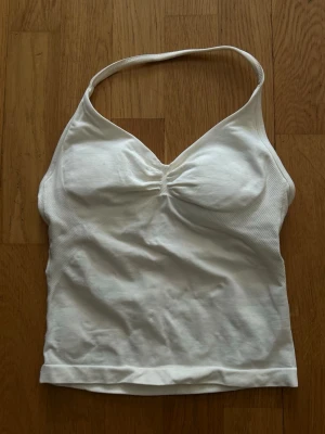 DFYNE Impact Longline Strappy Top - Säljer en DFYNE Impact Longline Strappy Top i färgen ”Ivory” med inbyggd sport-bh i st XS, endast använd fåtal gånger hemma då den är för liten vid brösten. Original pris 52,95€ - ca 580kr. Finns orderbekräftelse och DFYNE-tag bak om man vill se för äkthets bevis!!