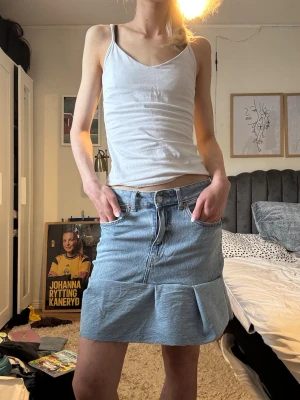 Ljusblå jeanskjol med volang - Trendig ljusblå jeanskjol med volangdetalj nedtill och klassisk femficksdesign. Kjolen har normal passform och stängs med knapp och dragkedja framtill. Perfekt för dig som gillar en avslappnad men ändå stilsäker look. Jag har gjort den själv, därav inte helt perfekt!!❤️ Skriv om du har några frågor eller vill ha flera bilder.😊