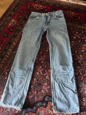 Ljusblå raka jeans i denim - Säljer ett par klassiska ljusblå jeans med rak passform och fem fickor. Jeansen har normal midja och är tillverkade i slitstark denim. Perfekta för en avslappnad och tidlös stil. Inget synligt märke på byxorna. Zara