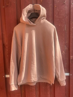 Uniqlo hoodie brun/beige - En beige oversized Uniqlo hoodie med huva och långa ärmar. Hoodien har en enkel och clean design utan tryck eller logga, samt ribbade muddar vid ärmslut och nederkant. Sitter bra på någon 175-180cm