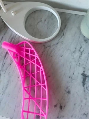 Rosa AIR hårtorkfäste i plast - Säljer ett rosa hårtorkfäste från AIR i plast. Fästet har ett rutnät och är böjt för att passa runt huvudet, perfekt för att torka håret snabbare och enklare. Smidig att använda och lätt att rengöra.
