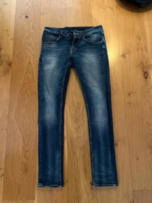 Tiger of seeden slim fit jeans med slitningar - Snygga blå slim fit jeans med lätt slitna detaljer och klassisk femficksdesign. Jeansen har en något tvättad look och raka ben. 31/32