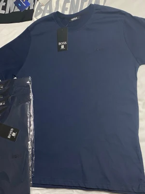 Marinblå BOSS t-shirt i bomull - Snygg marinblå t-shirt från BOSS med diskret logga på bröstet. Klassisk rund halsringning och korta ärmar. Tillverkad i mjuk bomull som känns skön mot huden. Perfekt basplagg för en clean och stilren look.
