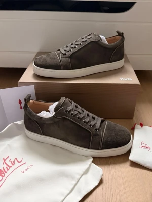 Christian Louboutin - Snygga bruna sneakers i mocka från Louboutin med vita sulor och ton-i-ton snörning. Klassisk låg modell med stilrena detaljer och diskret branding. Perfekta för dig som gillar exklusiva och tidlösa skor med premiumkänsla.