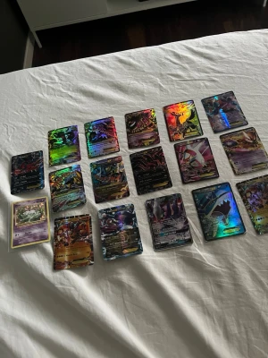 Samling Pokémonkort GX/EX.  - Säljer en samling Pokémonkort med flera GX, EX och VMAX-kort. Korten har färgglada och holografiska motiv med olika Pokémon. Perfekt för samlare eller dig som vill utöka din kortlek. Blandade motiv och färger, mestadels glansiga ytor.