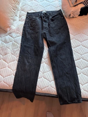 Svarta raka jeans - Säljer ett par svarta jeans med rak passform. Jeansen har knappgylf och är tillverkade i denim. Storlek: 33/32 (se bild)