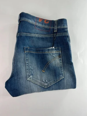 Dondup med slitningar  - Snygga blå jeans med tvättad färg och slitningar. Jeansen är aldrig andvända och passar perfekt till alla kläder. 
