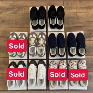 Svarta sneakers Maison Margiela - Snygga svarta sneakers från Maison Margiela med klassisk låg siluett och vita sulor. Skorna har en stilren design med diskreta detaljer och är tillverkade i mocka och läder för en exklusiv känsla.
