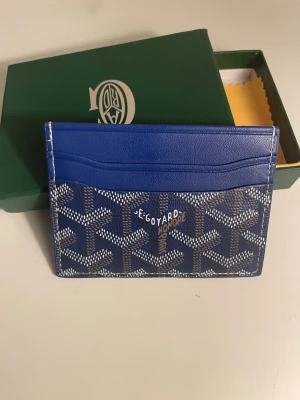 Blå G4yard korthållare - Snygg blå korthållare från G4yard med klassiskt mönster och vit logga framtill. Tillverkad i canvas och läder med flera kortfack. Perfekt för dig som vill ha en stilren och exklusiv accessoar i fickan.