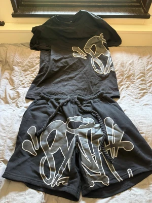 Svart set med graffiti-tryck - Tröjan är storlek M och shorten storlek L. Riktigt snyggt set inför sommaren. 