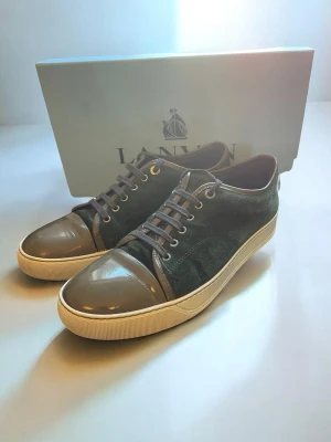 Lanvin sneakers i grön mocka  - Snygga sneakers från Lanvin med mörkgrön mocka och grått lack på tån och hälen. Skorna är i storlek 10 vilket passar som 44. Bara att höra av sig vid frågor