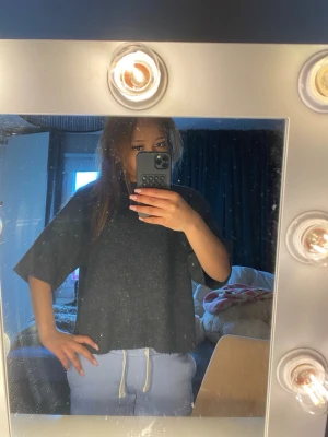 Stickad tröja  - Säljer en oversized mörkgrå t-shirt med korta ärmar. T-shirten har en enkel och avslappnad passform, perfekt för en chill och stilren look. Materialet känns mjukt och bekvämt mot huden.
