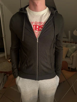 Mörkgrå hoodie med blixtdetaljer - Mörkgrå zip-hoodie med huva. Säljer då den inte kommer till användning. Pris går att diskuteras