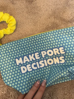Blå necessär från Benefit - Rolig necessär från Benefit i blått med vita prickar och texten 'MAKE PORE DECISIONS' på framsidan. Perfekt för smink eller småprylar när man reser iväg