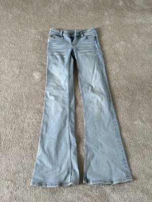 Bootcut ljusa utsvängda jeans - Säljer ett par ljusblå utsvängda jeans från Bootyseven. Klassisk femficksmodell med knapp och dragkedja framtill. Jeansen har en snygg bootcut-passform och är tillverkade i bomull med en skön känsla.