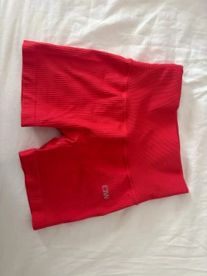Röda ribbade träningstights-shorts - Snygga röda träningstights-shorts från ICANIWILL med hög midja och ribbad struktur. Perfekta för gymmet eller löprundan. Stretchigt material som ger en bekväm och smickrande passform. Diskret logga framtill.