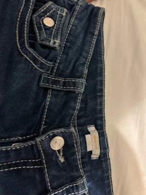 Low waist bootcut jeans från Gina Tricot  - Snygga mörkblå bootcut jeans med vita kontrastsömmar och klassiska fickor både fram och bak. Jeansen har låg midja och är tillverkade i stretchigt denim för en bekväm passform. Perfekta för dig som gillar en tidlös och trendig look. Från Young linjen på Gina Tricot. Köpta för 399kr
