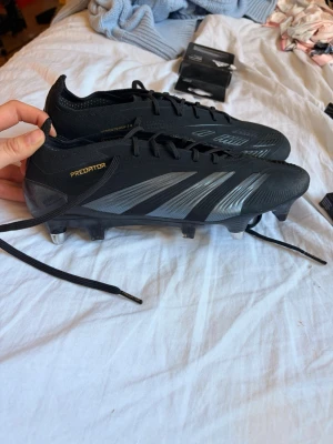 Adidas Predator svarta fotbollsskor - Snygga svarta Adidas Predator fotbollsskor med silvriga detaljer och klassisk snörning. Skorna har metalldobbar och kommer även med flera på köpet. Endast använda en gång. Köpte de för 3300kr. Kan gå med på prissänkning under snabb affär. (Påsen ingår i köpet.