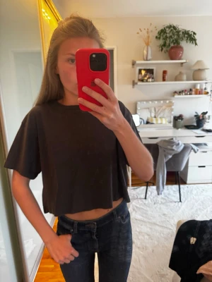 Svart croppad t-shirt - En enkel svart croppad t-shirt med lös passform och korta ärmar. Perfekt till jeans eller kjol för en avslappnad look. Tillverkad i mjukt bomullstyg som känns skönt mot huden.