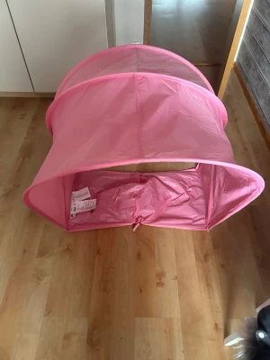 Rosa lektunnel från IKEA - Säljer en rosa lektunnel från IKEA i lättviktigt tyg och plast. Perfekt för lek och bus inomhus, enkel att fälla ihop och förvara. Tunneln är bågformad och har öppningar i båda ändar. Passar bra för barn som gillar att krypa och leka.