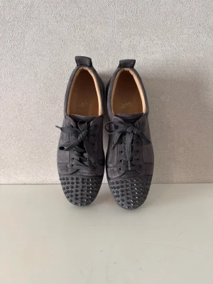  Christian Louboutin sneakers - Tja jag säljer ett par gråa Christian Louboutin sneakers med nitar! Storlek 43, skick 8/10! Äkta, har kvitto!  Skicket är bra förutom en liten skavank på insidan av ena skon fråga efter bilder om ni vill ha på just det! MVH freddysgarderob