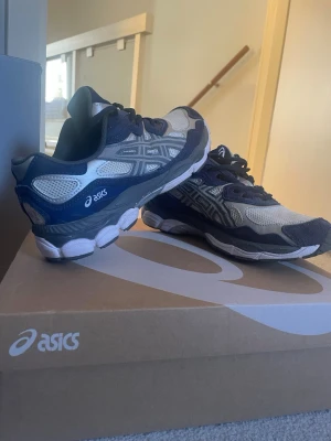 ASICS Gel-1090 sneakers blå/grå - Snygga ASICS Gel-1090 sneakers i blått och grått med vita detaljer. Skorna har en låg profil, mesh- och syntetmaterial för bra ventilation och komfort. Klassisk ASICS-logga på sidan och robust sula som ger bra stöd. Perfekt för dig som gillar sportig stil.