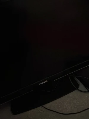 Svart Philips TV-skärm - Säljer en svart TV-skärm från Philips med stilren design. Skärmen har rektangulär form och är tillverkad i plast och glas. Perfekt för gaming, film eller som extra skärm till datorn. Strömkabel och fot medföljer.