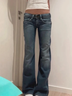 Lågmidjade bootcut jeans - Säljer ett par blå vintage 2000s bootcut jeans med låg midja och snygga detaljer. Märket är Pepe jeans och storleken är 28/34 vilket passar mig som brukar bära S i jeans och är 172 cm lång. Kontakta privat för ytterligare mått💕💕