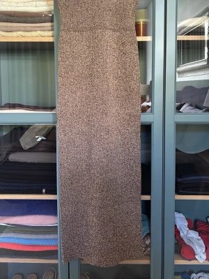 Beige stickad klänning med slits - Snygg beige stickad klänning med rak passform och slits baktill. Kjolen har en ribbad midja som ger en bekväm och följsam känsla. Perfekt att styla med en enkel topp eller stickad tröja.