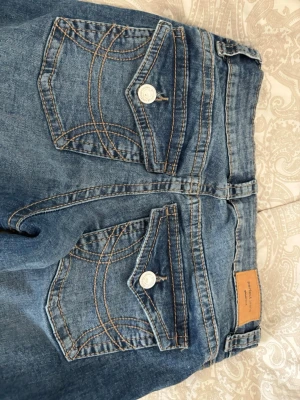 Blå bootcut jeans från Gina  - Skriv om ni vill ha fler bilder! Snygga blå bootcut jeans från Gina med slitningar på låret och coola bakfickor med lock och dekorativa sömmar. Klassisk femficksmodell med knapp och dragkedja. Perfekta för en avslappnad och trendig look. Aldrig använda då dem är lite långa på mig som är 159. 