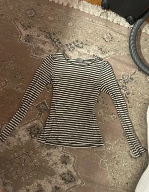Randig långärmad topp Vero Moda - Säljer en slim fit långärmad topp från Vero Moda i vitt och mörkgrönt med klassiskt randigt mönster. Toppen är ribbad och har rund halsringning, perfekt att styla med jeans eller kjol.