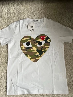 Vit t-shirt från Comme des Garçons Play - Vit t-shirt från Comme des Garçons Play. Mycket fint skick, helt ny endast testad, fraktar inom 24 timmar (instabox). Skriv vid frågor eller funderingar!