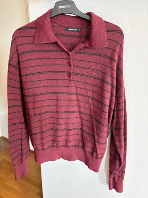 Vinröd randig tröja med krage - Vinröd långärmad tröja från Gina Tricot med svarta horisontella ränder och klassisk krage. Tröjan har tre knappar framtill och ribbade muddar vid ärmslut och nederkant. Perfekt för en avslappnad och cool look.