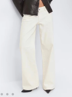 Vida vita jeans med låg midja - Snygga vita jeans med hög midja och vida ben. Klassisk femficksmodell med knapp och dragkedja framtill. Perfekta för dig som gillar en relaxed och trendig look. Materialet är denim och färgen är krämvit.
