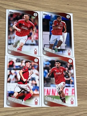 Nottingham Forest fotbollskort Topps - Fyra samlarkort från Topps med spelare från Nottingham Forest. Kortens framsida har actionbilder i röd matchtröja och vit shorts, med namn och position. Baksidan innehåller spelarinformation och klubbens logotyp. Perfekt för fotbollsfans och samlare.