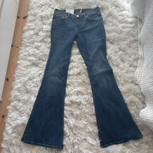 Blå flare jeans från Monki, 29/32 - Snygga blå jeans från Monki i modellen Katsumi med låg midja och flare fit. Helt nya aldrig använda