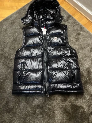 Svart Moncler väst - Säljer en ny svart moncler väst använd 2-3 gånger. Anledning varför jag säljer den:Den är för stor på mig 